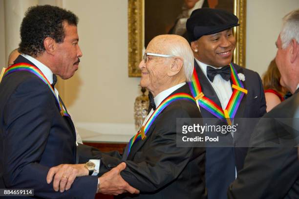 Lionel Richie, left, shares an embrace with Norman Lear, left center, while LL COOL J, center right, converses with United States Secretary of State...