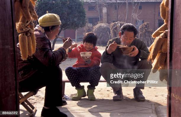 Chen Xiao Sa, 8 years old child of migrant worker parents, having lunch with grandparents in Dong Da Jian village, Shaanxi Province.