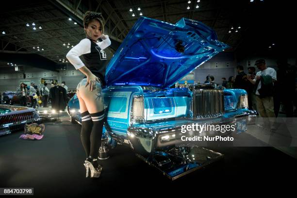 Model poses for the cameras next to the custom hot rod car is shown during the 26th Annual Yokohama Hot Ror Custom Show 2017, December 3, 2017 in...