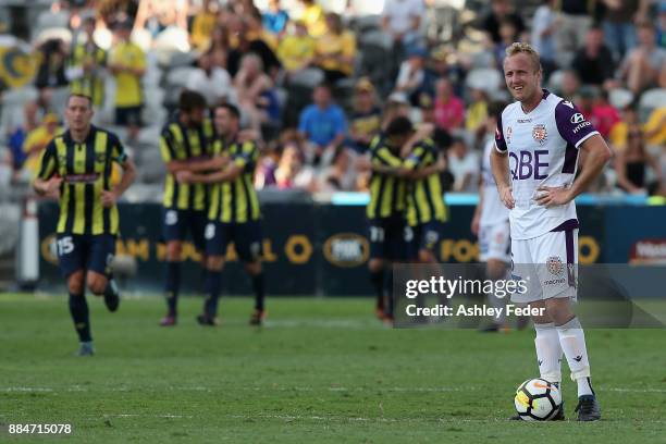 Mitch Nichols of Perth Glory is dejected at full time with Mariners celebrating in the background during the round nine A-League match between the...