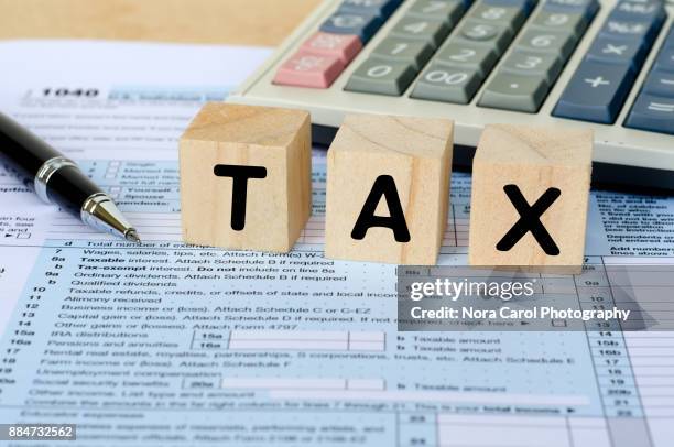 tax word on wooden block with calculator and tax form - 1040 2017 stock pictures, royalty-free photos & images