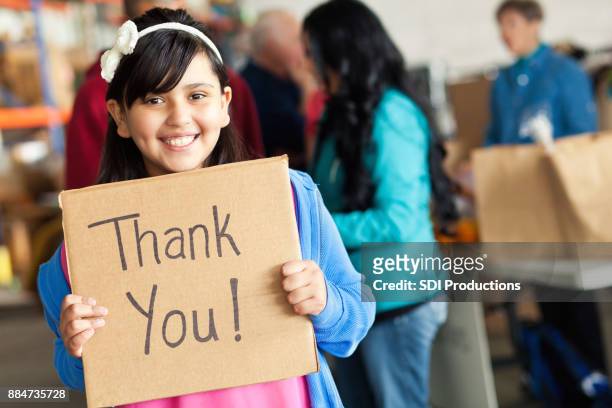 adorable little girl holds thank you sign during food drive - child holding sign imagens e fotografias de stock