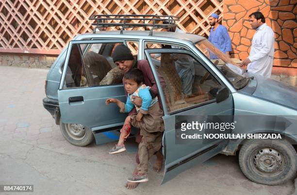 An Afghan youth carries an injured boy to hospital after a suicide attack in Jalalabad on December 3, 2017. - At least six people were killed after a...