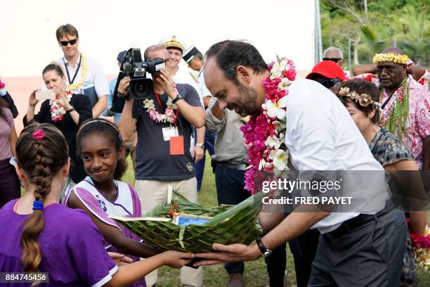 French Prime Minister Edouard Philippe receives a gift as he meets pupils and teachers of the public school on Tiga island, in the archipelago of the...