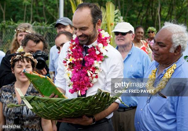 French Prime Minister Edouard Philippe reacts after receiving a gift during a meeting with pupils and teachers of the public school on Tiga island,...
