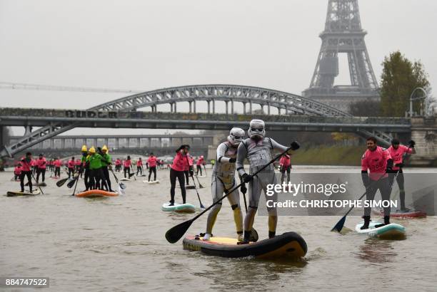 Competitors in fancy dress Star Wars Stormtrooper costumes paddle by while taking part in the Nautic Sup Paris crossing stand up paddle race along...