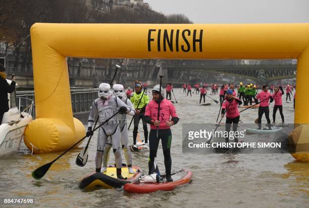Competitors in fancy dress Star Wars Stormtrooper costumes finish the Nautic Sup Paris crossing stand up paddle race along the Seine River in Paris...