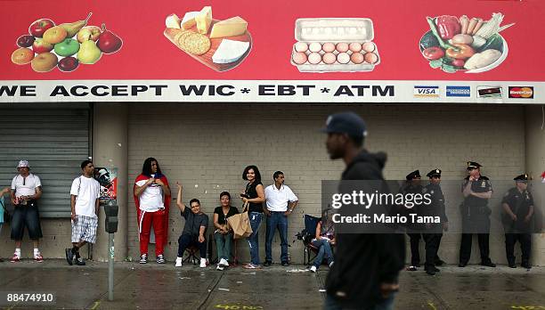 Revelers and police take shelter from the rain during the 116th Street Festival in Spanish Harlem June 13, 2009 in New York City. The 28-block...