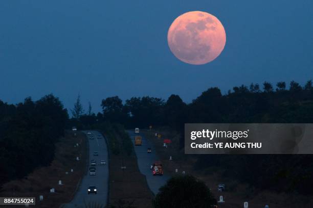 The supermoon rises over a highway near Yangon on December 3, 2017. The lunar phenomenon occurs when a full moon is at its closest point to earth.