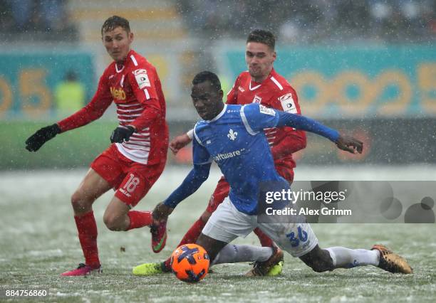 Wilson Kamavuaka of Darmstadt and Marc Lais and Jonas Nietfeld of Regensburg battle for the ball during the Second Bundesliga match between SV...