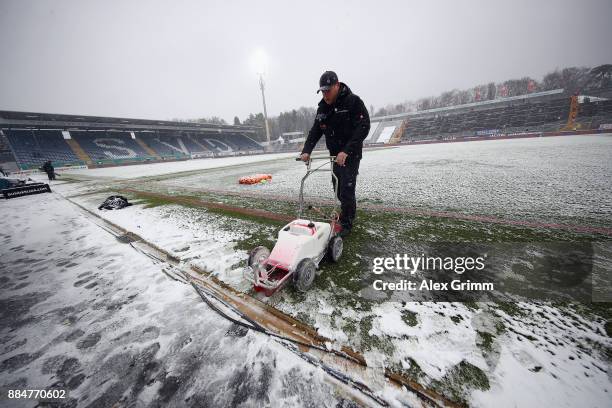 Stadium worker prepares the snow covered pitch prior to the Second Bundesliga match between SV Darmstadt 98 and SSV Jahn Regensburg at Merck-Stadion...