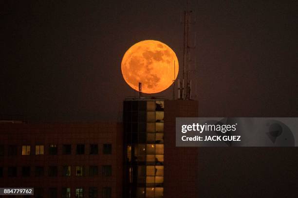 The 'supermoon' rises over a building in the Israeli city of Netanya, on December 3, 2017. The lunar phenomenon occurs when a full moon is at its...