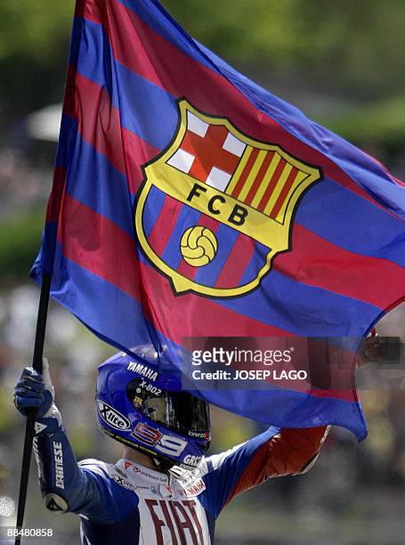 Yamaha's Spanish Jorge Lorenzo waves a flag of the FC Barcelona football club in celebration after finishing second during the Moto GP race of the...