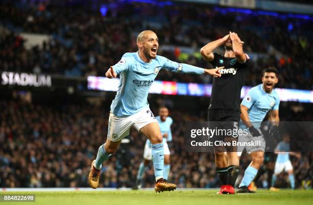 David Silva of Manchester City celebrates scoring his sides second goal while Pablo Zabaleta of West Ham United looks dejected during the Premier...