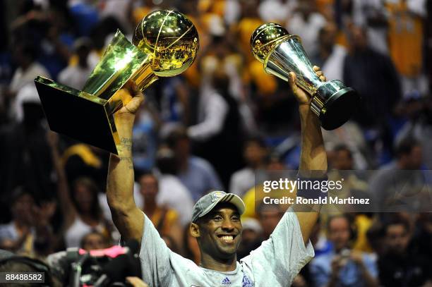 Kobe Bryant of the Los Angeles Lakers holds up the Larry O'Brien trophy and the MVP trophy after the Lakers defeated the Orlando Magic 99-86 in Game...