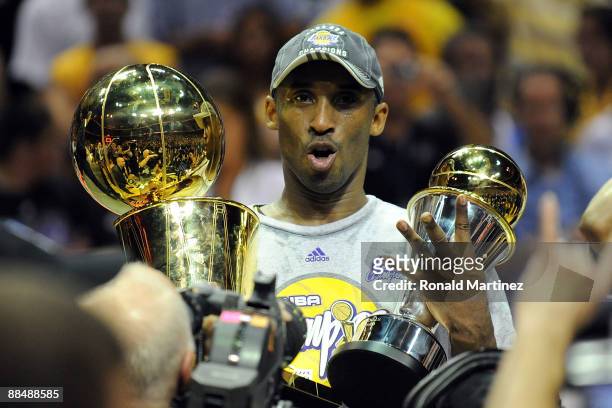 Kobe Bryant of the Los Angeles Lakers holds up the Larry O'Brien trophy and the MVP trophy after the Lakers defeated the Orlando Magic 99-86 in Game...
