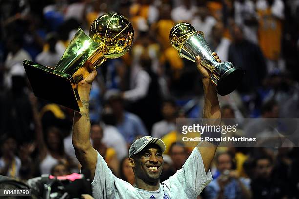 Kobe Bryant of the Los Angeles Lakers holds up the Larry O'Brien trophy and the Bill Russell MVP trophy after the Lakers defeated the Orlando Magic...