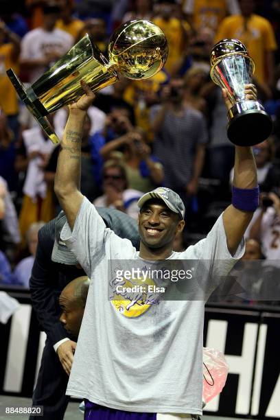 Kobe Bryant of the Los Angeles Lakers holds up the Larry O'Brien trophy and the Bill Russell MVP trophy after the Lakers defeated the Orlando Magic...