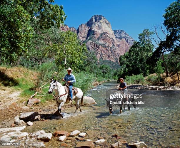 Zwei Reiter ueberqueren den Virgin River im 1919 gegruendeten Zion Nationalpark, einer schluchtenreichen Naturlandschaft mit unterschiedlichen...