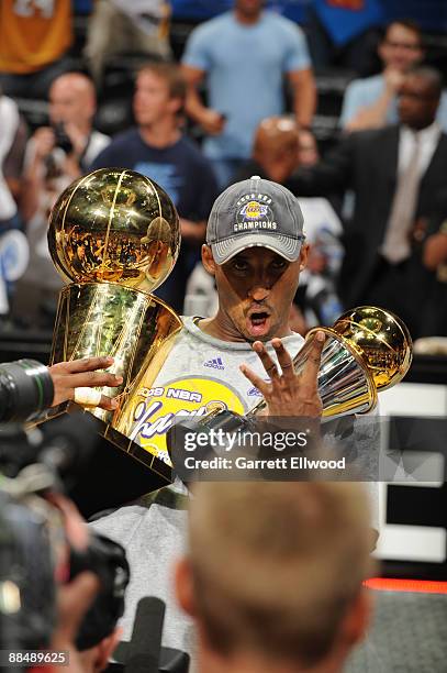 Kobe Bryant of the Los Angeles Lakers poses with the Larry O' Brien and Bill Russell MVP trophy after defeating the Orlando Magic in Game Five of the...