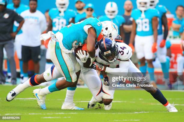 Kenyan Drake of the Miami Dolphins rushes during the second quarter against Will Parks of the Denver Broncos at the Hard Rock Stadium on December 3,...
