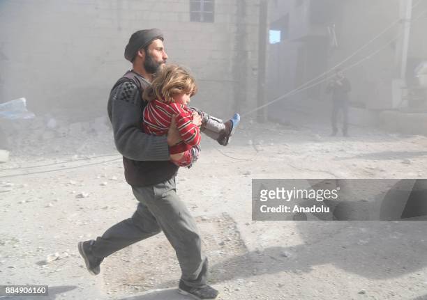 Syrian man runs with his daughter following the Assad regime's air strikes over residential areas in the de-escalation zone in the Eastern Ghouta...