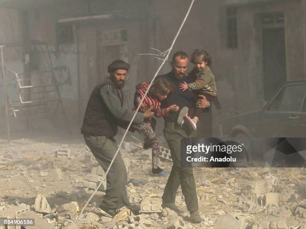 Syrians run with their children following the Assad regime's air strikes over residential areas in the de-escalation zone in the Eastern Ghouta...