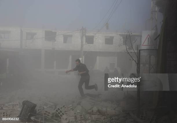 Syrians are seen through following the Assad regime's air strikes over residential areas in the de-escalation zone in the Eastern Ghouta region in...