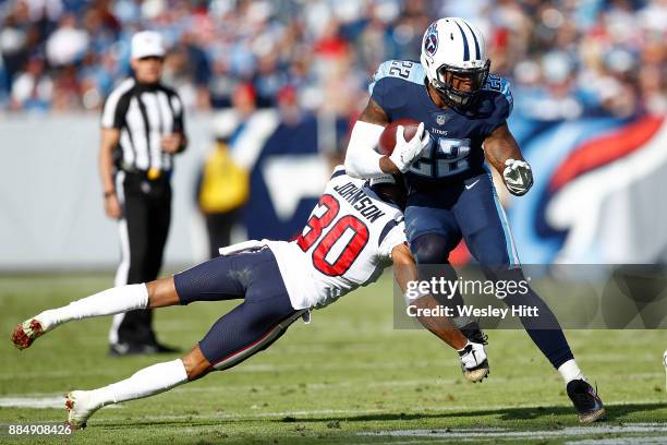 Derrick Henry of the Tennessee Titans breaks a tackle from Kevin Johnson of the Houston Texans during the first half at Nissan Stadium on December 3,...