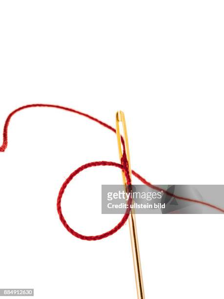 Ein roter Faden in einem Nadelöhr eingefädelt. Konzept für Erfolg im Handwerk als Schneider.