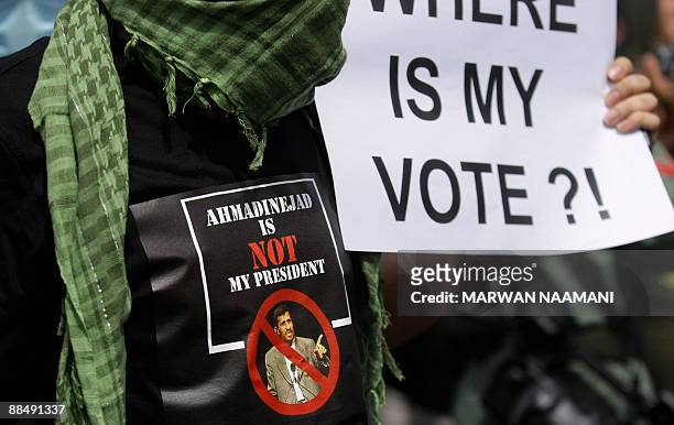 An Iranian protester, spotring a T-shirt with a picture of the Islamic republic's reelected President Mahmoud Ahmadinejad with the slogan...