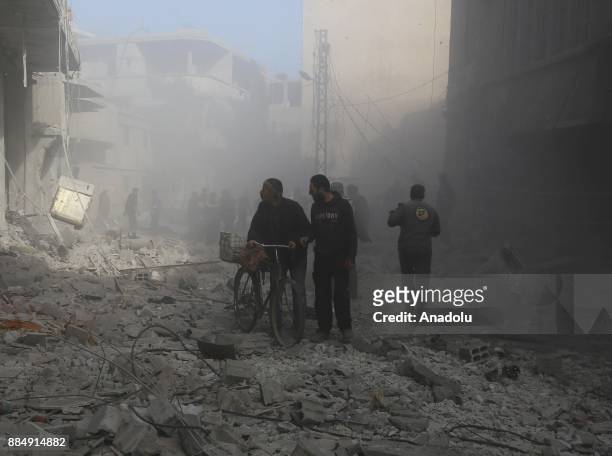 Syrians are seen on wreckage of collapsed buildings following the Assad regime's air strikes over residential areas in the de-escalation zone in the...