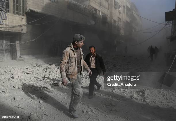 Syrians are seen on wreckage of collapsed buildings following the Assad regime's air strikes over residential areas in the de-escalation zone in the...