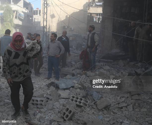 Syrians are seen on wreckage of collapsed buildings following the Assad regime's air strikes over residential areas in the de-escalation zone in the...