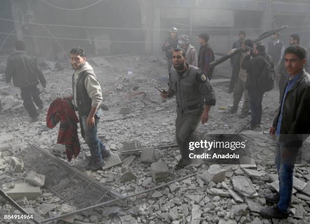 Syrians are seen on wreckage of collapsed buildings following the Assad regime's air strikes over residential areas in the de-escalation zone in the...