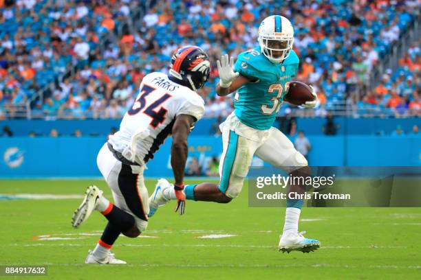 Kenyan Drake of the Miami Dolphins rushes during the third quarter against Will Parks of the Denver Broncos at the Hard Rock Stadium on December 3,...