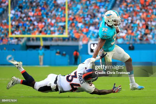 Kenyan Drake of the Miami Dolphins rushes during the third quarter against Will Parks of the Denver Broncos at the Hard Rock Stadium on December 3,...