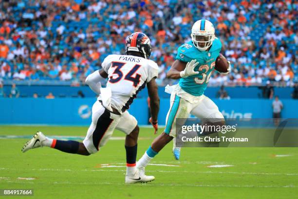 Kenyan Drake of the Miami Dolphins rushes during the third quarter against Will Parks of the Denver Broncos at the Hard Rock Stadium on December 3,...