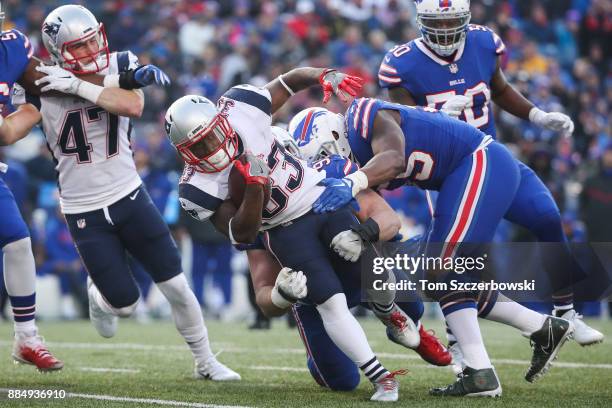 Dion Lewis of the New England Patriots runs the ball as Kyle Williams of the Buffalo Bills and Jerry Hughes of the Buffalo Bills attempt to tackle...