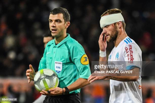 Marseille's French forward Valere Germain , wearing a band-aid on the head after being elbowed in the face, walks ne to referee Frank Schneider...