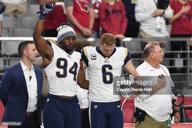 Outside linebacker Robert Quinn of the Los Angeles Rams raises his fist while standing with punter Johnny Hekker during the National Anthem before...