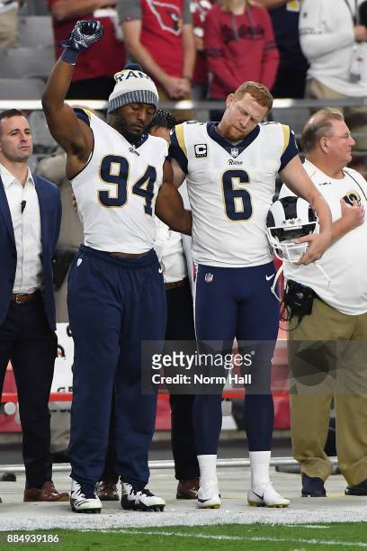 Outside linebacker Robert Quinn of the Los Angeles Rams raises his fist while standing with punter Johnny Hekker during the National Anthem before...