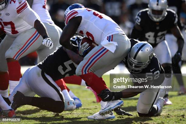 Orleans Darkwa of the New York Giants is tackled for a loss by Khalil Mack and NaVorro Bowman of the Oakland Raiders during their NFL game at...