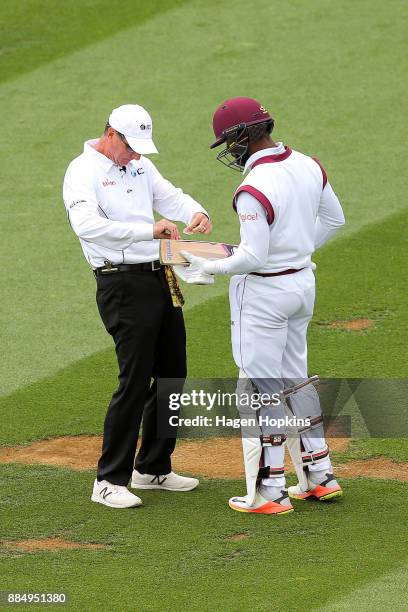 Shai Hope of the West Indies gets some running repairs to his bat from umpire Rod Tucker of Australia during day four of the Test match series...