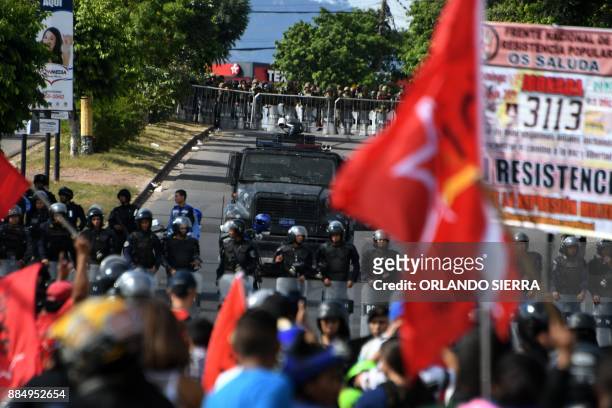 Soldiers and police block the road as thousands of supporters of the presidential candidate for Honduras' Opposition Alliance against the...