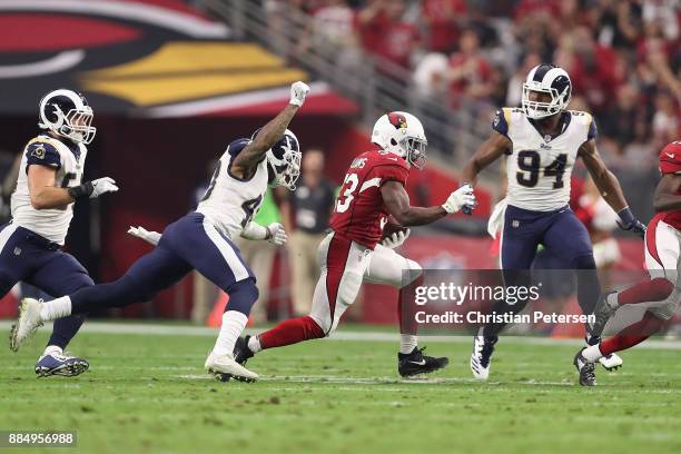 Running back Kerwynn Williams of the Arizona Cardinals runs past strong safety John Johnson of the Los Angeles Rams during the first half of the NFL...