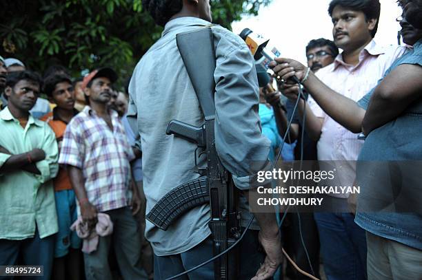 An armed Maoist activist speaks with media representatives as Indian activists of the People's Committee Against Police Atrocities demolish a party...