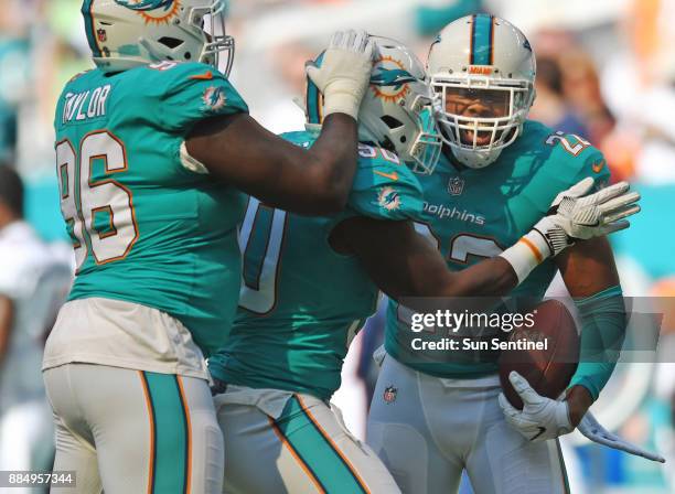 Miami Dolphins strong safety T.J. McDonald celebrates an interception with teammates Charles Harris and Vincent Taylor against the Denver Broncos on...