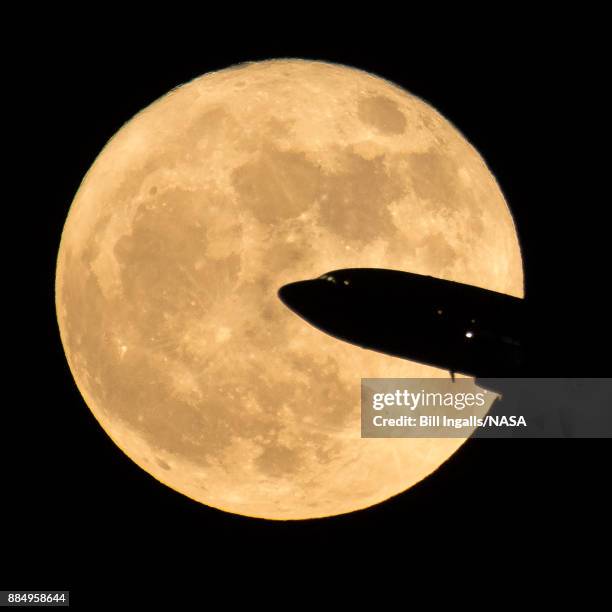 In this handout provided by NASA, an aircraft taking off from Ronald Reagan National Airport is seen passing in front of the moon as it rises on...