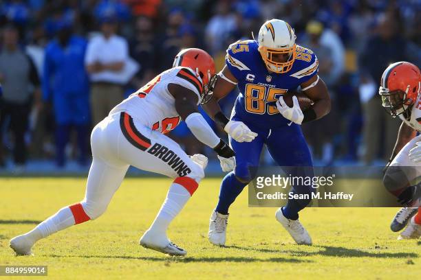 Antonio Gates of the Los Angeles Chargers runs the ball down field but later gets tackled by James Burgess of the Cleveland Browns and Christian...